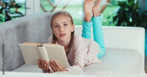 Portrait cheerful girl 9 years relaxing with book on the sofa in the living room
