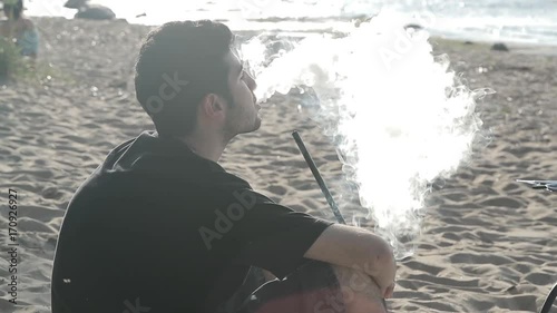 Guy smokes hookah on the beach In slow motion photo