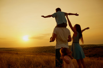 Happy family in the field at sunset.