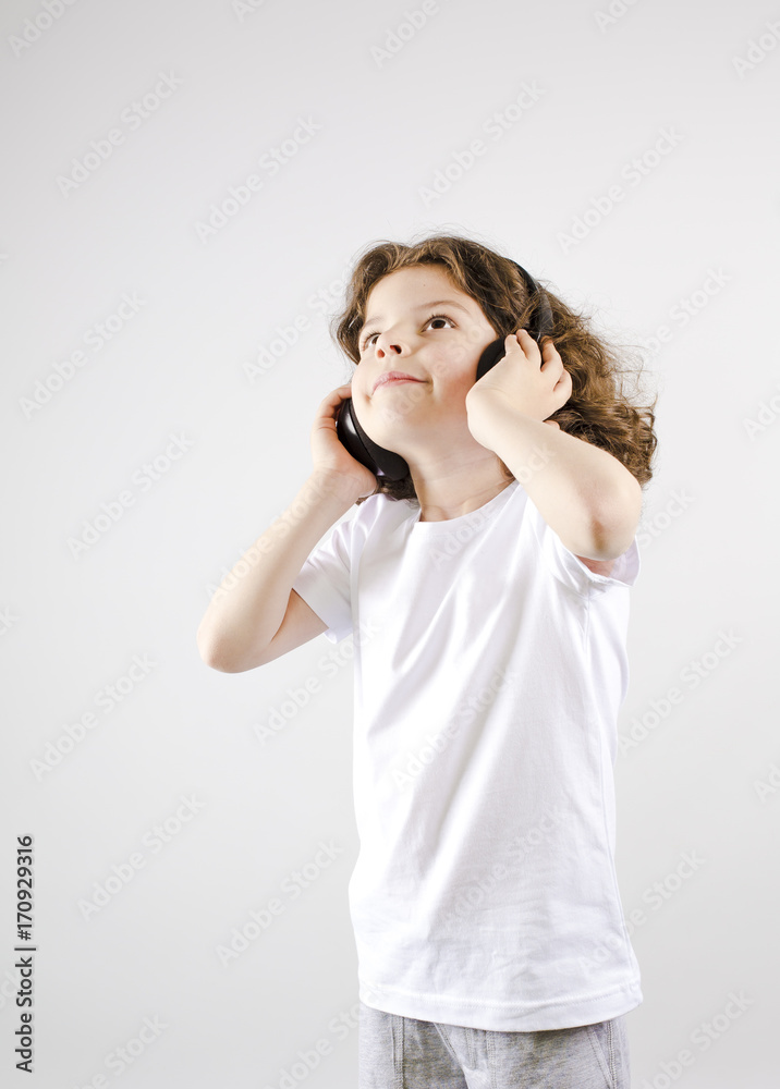Music and technology concept.Caucasian little boy with headphone on gray background Music and technology concept.Caucasian little boy with headphone on gray background