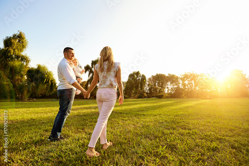 Happy young family in the park at sunset.