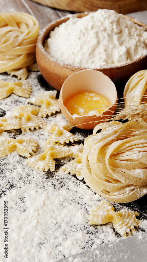 Uncooked pasta with flour on the table, selective focus Uncooked pasta with flour on the table, selective focus