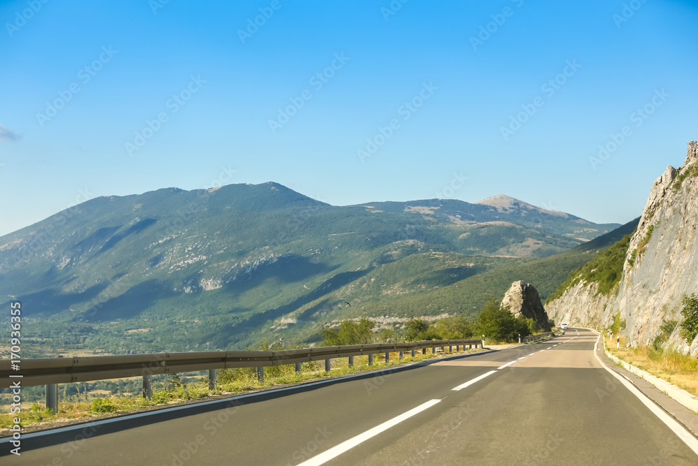 Road through the rural landscape under clear blue sky.