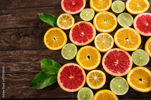 slices of oranges, limes, grapefruit and lemons. Over wood table background with copy space.