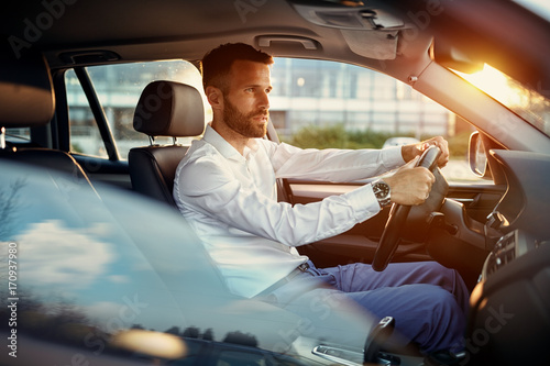 Young businessman driving car.