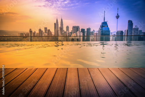 Canvas Print Cityscape of Kuala lumpur city skyline with swimming pool on the roof top of hotel and wooden floor at sunrise in Malaysia