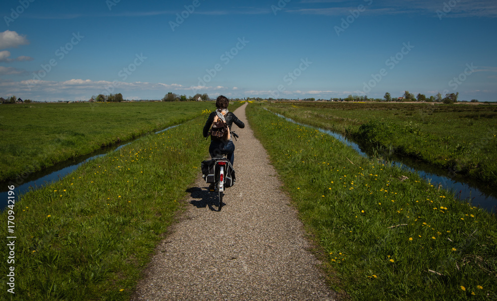 Obraz premium Girl on bike in Dutch fields