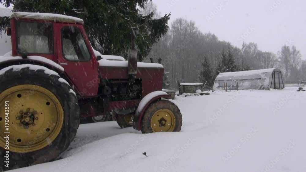 Snowfall in farm on old retro tractor and plastic greenhouse Snowfall in farm on old retro tractor and plastic greenhouse