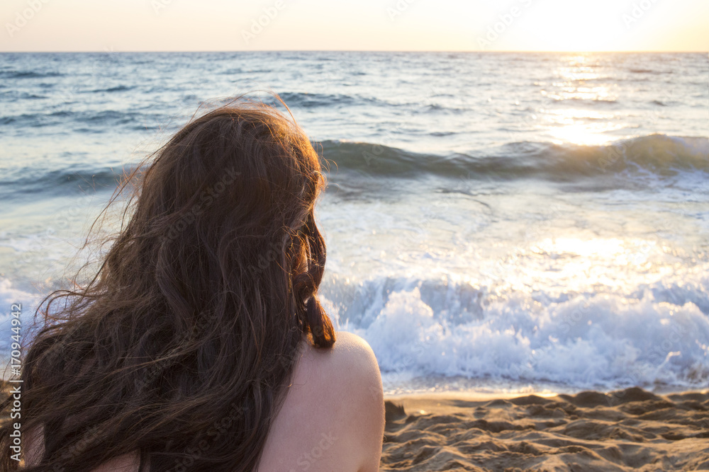 Una giovane e bella ragazza mora guarda il tramonto in spiaggia. Vediamo le sue spalle bianche e l'orizzone dove il sole sta calando nell'ora del tramonto. Le vacanze sono quasi finite. Una giovane e bella ragazza mora guarda il tramonto in spiaggia. Vediamo le sue spalle bianche e l'orizzone dove il sole sta calando nell'ora del tramonto. Le vacanze sono quasi finite.