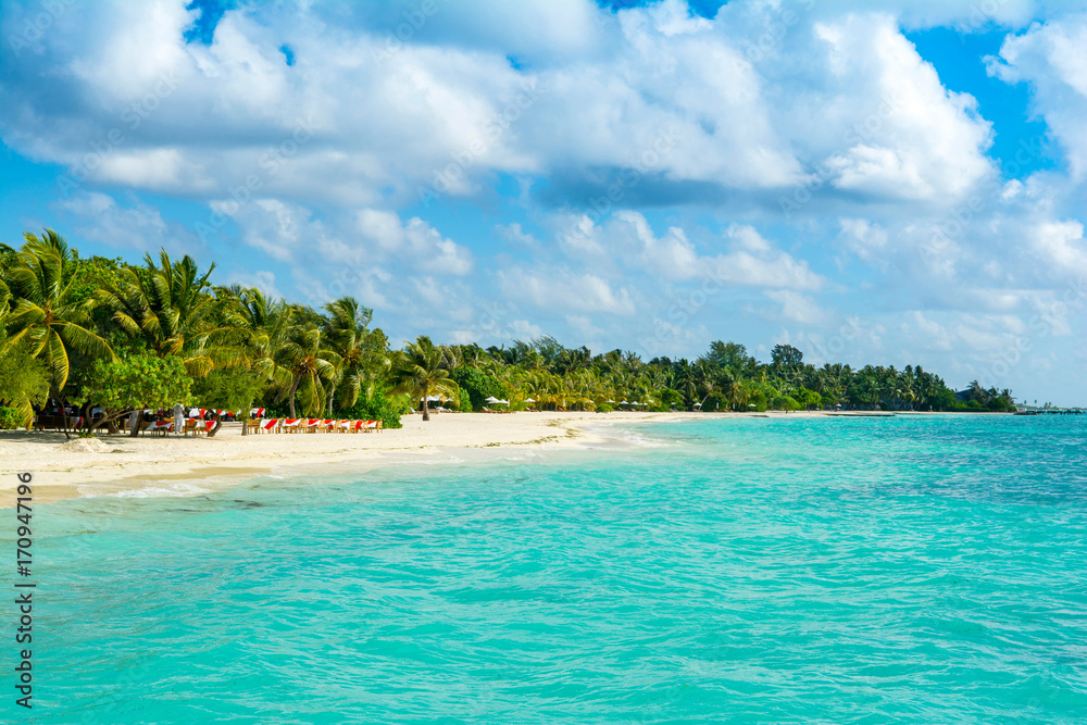 Beautiful sandy beach with sunbeds and umbrellas in Indian ocean, Maldives island