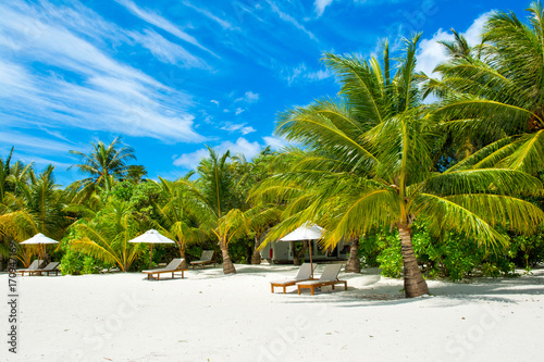 Beautiful sandy beach with sunbeds and umbrellas in Indian ocean, Maldives island