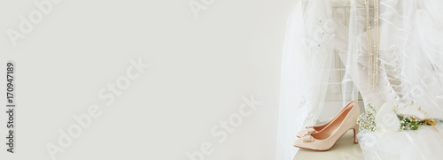 Obraz na płótnie Beautiful white wedding dress, shoes, gold diamond tiara and veil on chair