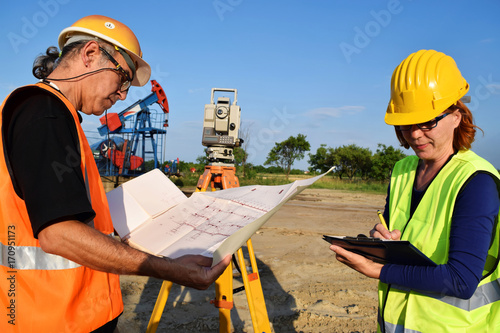 Two engineers - land surveyors at work on an European oil well 