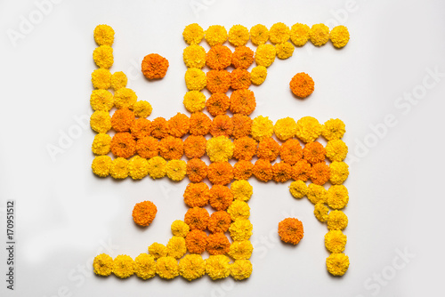 stock photo of hindu auspicious symbol called Swastika made using marigold flower or zendu or genda phool, Flower rangoli in the shape of Swastika for diwali/pongal/onam over white background
