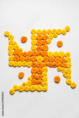 stock photo of hindu auspicious symbol called Swastika made using marigold flower or zendu or genda phool, Flower rangoli in the shape of Swastika for diwali/pongal/onam over white background
