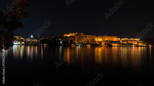 Udaipur cityscape by night. The majestic city palace reflecting lights on Lake Pichola, travel destination in Rajasthan, India. © fabio lamanna
