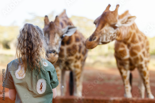 Cute little girl feeding giraffes in Africa © BlueOrange Studio