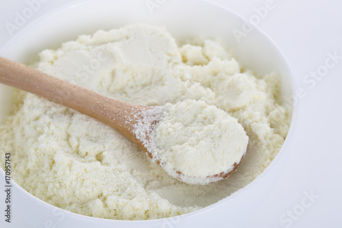 A bowl of milk powder and spoon. Close up.