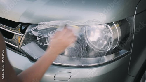 Car owner uses wax or soap to polish and clean front lights of his car or van at sef service high pressure wash or at garage, concept consumerism, perfectionist, ownership photo