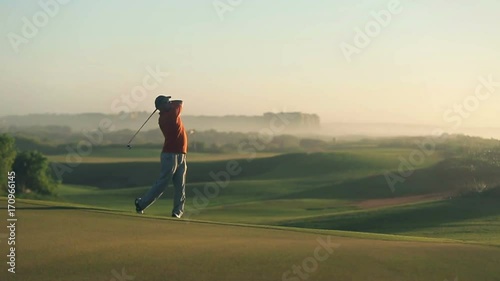 Man playing golf at sunset