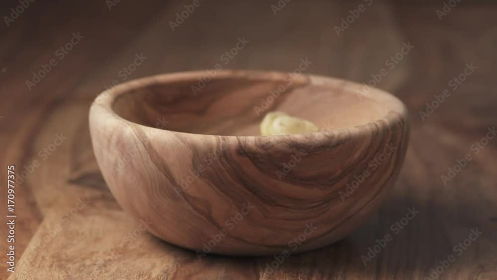 Slow motion potato chips with black pepper falling in wooden bowl on wood table Slow motion potato chips with black pepper falling in wooden bowl on wood table