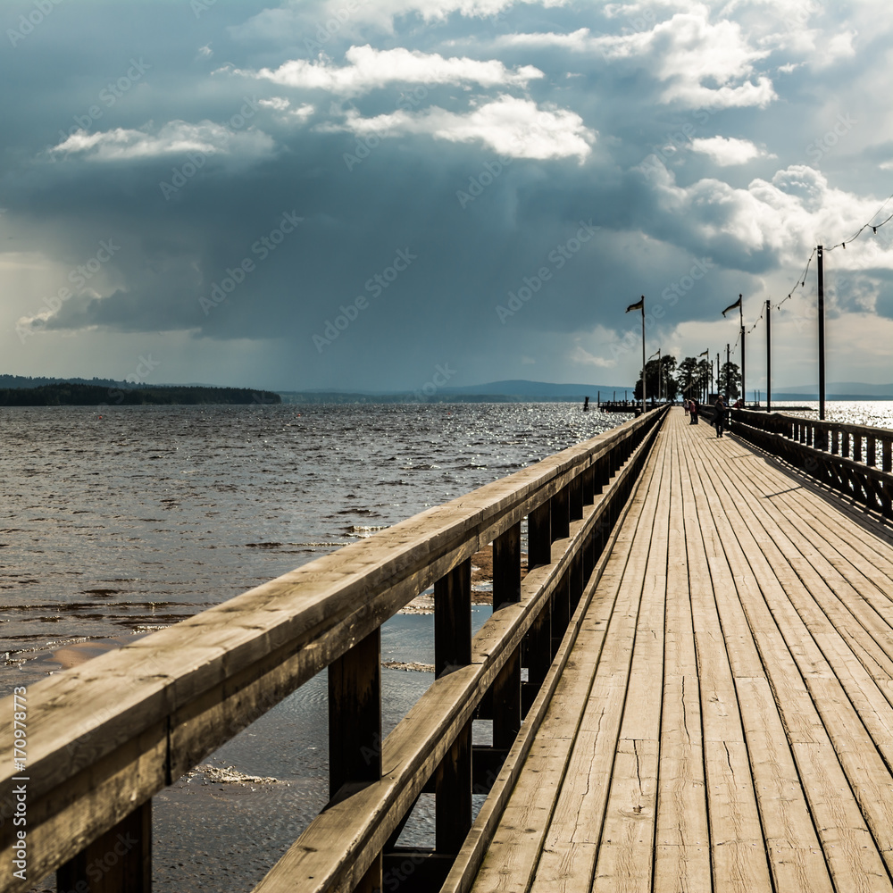 Wooden boardwalk in Rattvik, Sweden, under overcast sky - square.
