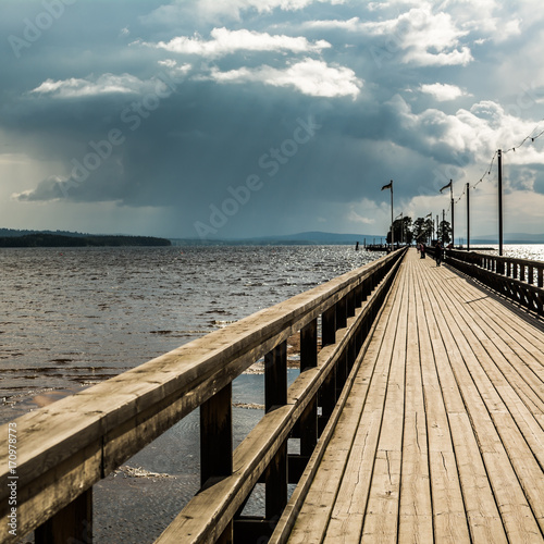 Wooden boardwalk in Rattvik, Sweden, under overcast sky - square. photo