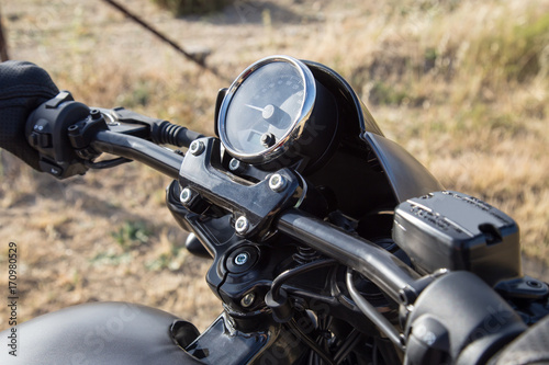 Handlebar of a motorcycle held by the biker in the field. 