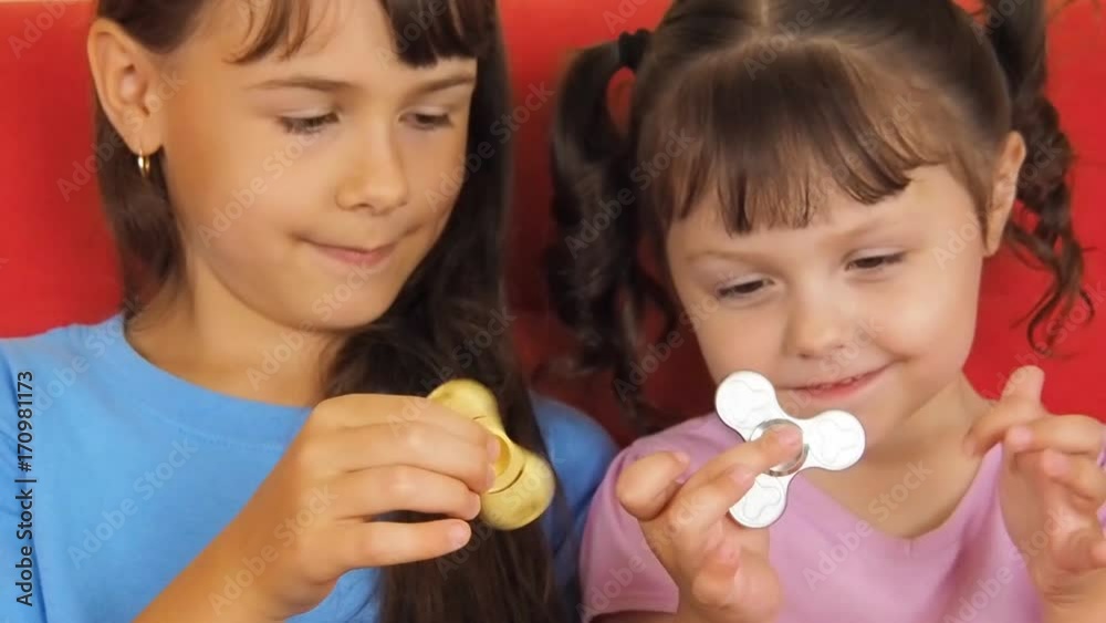 Little girls twist the spinner. Sisters twist the spinner. Little girls twist the spinner. Sisters twist the spinner.