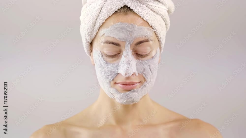 Beautiful attractive young woman is applying brand new a cream on her face isolated on beige background