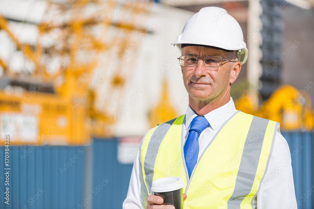 Engineer builder on construction site at sunny day with coffee in hand Engineer builder on construction site at sunny day with coffee in hand