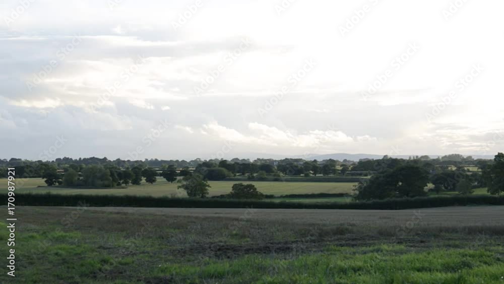 Rural autumnal landscape with brown mowed wheat field, Tarvin, Cheshire, England, UK. Overcast sky with mountains and trees in background. Rural autumnal landscape with brown mowed wheat field, Tarvin, Cheshire, England, UK. Overcast sky with mountains and trees in background.