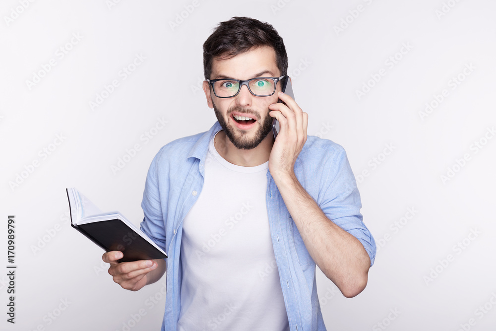 Closeup portrait of excited bug-eyed young handsome person wearing glasses surprised from receiving call keeping mouth wide open isolated on white. Human emotions, facial expression feelings concept. Closeup portrait of excited bug-eyed young handsome person wearing glasses surprised from receiving call keeping mouth wide open isolated on white. Human emotions, facial expression feelings concept.