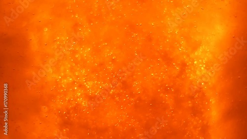 Bubbles floating in the amazing deep structured orange liquid. Blurred background with dimension. 