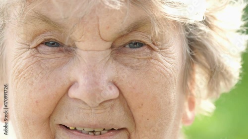 Portrait of smiling mature elderly woman with gray hair outdoors in the park in summer. Close-up photo