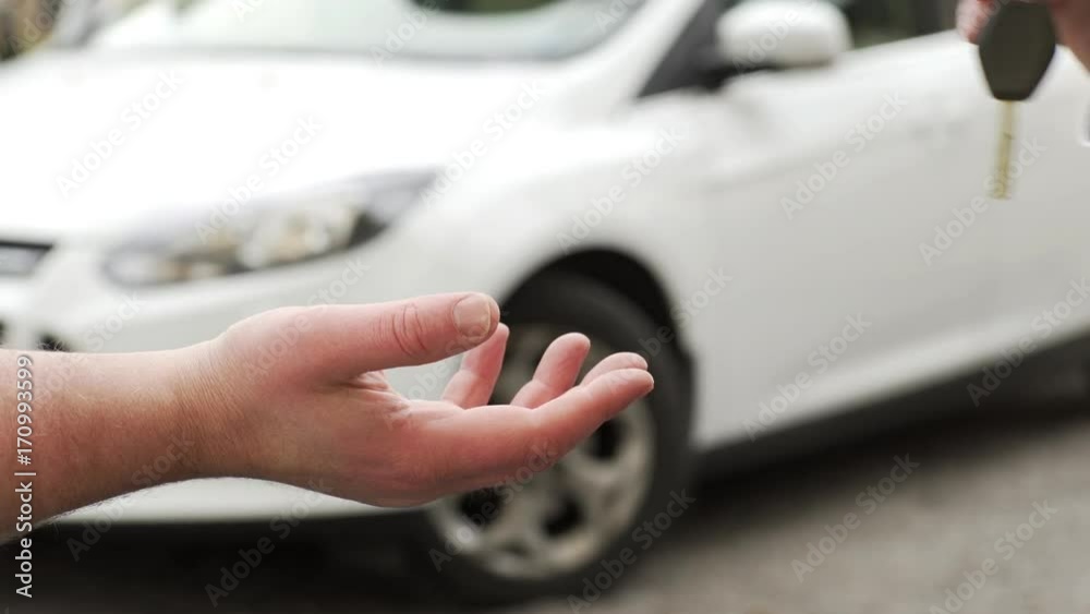 A car being bought / sold. A man buying / selling a car to another man and handing over the key.