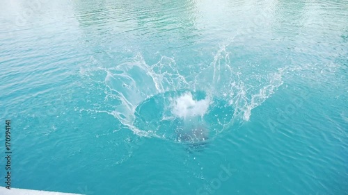 Teenager jumps into swimming pool. Caucasian boy cannonball jumping in the outdoor swimming pool.