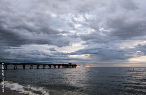 storm clouds rolling in over an ocean fishing pier at sunrise