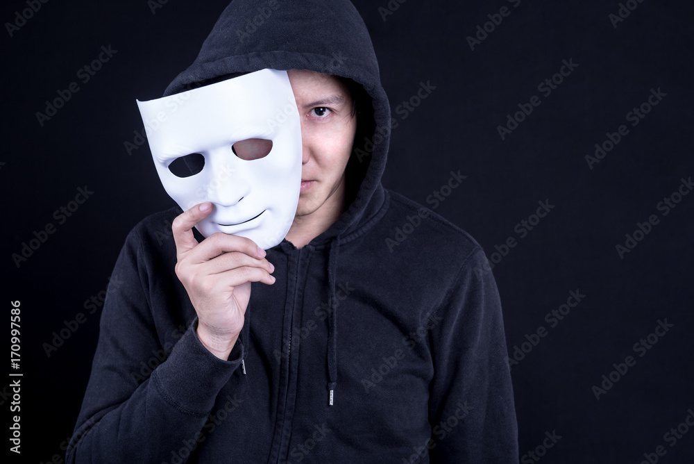 Mystery man holding white mask for hide his face. Anonymous social masking or halloween concept