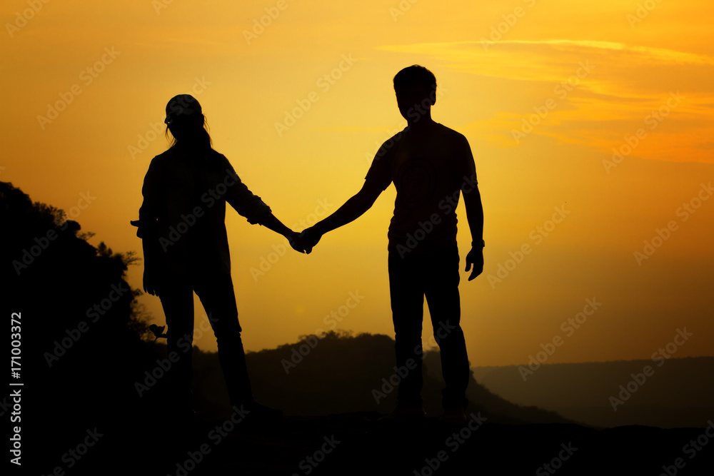 Silhouette couple's holding hand for travelers on sunrise