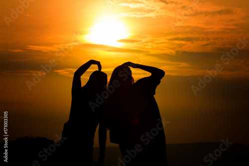 Silhouette of couple in love watching a sunset on the mountains, moment of reflection