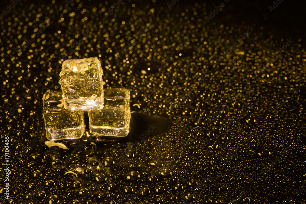 Ice cubes in yellow light on black wet table. Ice cubes in yellow light on black wet table.