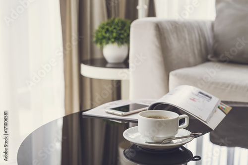 Cup of coffee on a round table with sofa in living room