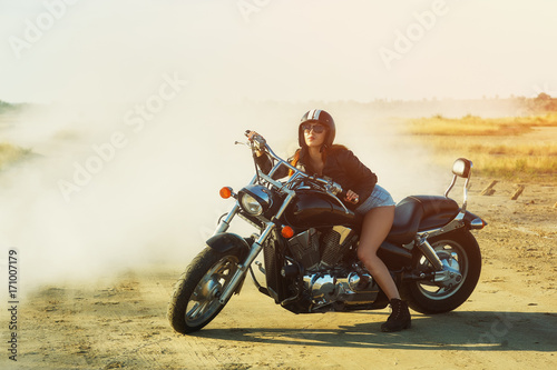 Fototapeta Naklejka Na Ścianę i Meble -  Attractive girl on a motorcycle on a dirt road