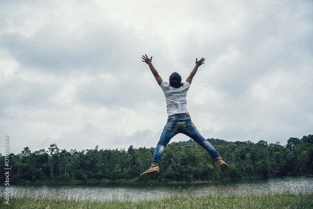 Asian man travel relax in the holiday. Jump on a green pasture. Asian man travel relax in the holiday. Jump on a green pasture.
