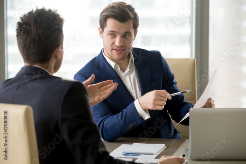 Successful businessman clarifying provisions of contract with business partner, discussing terms of agreement, explaining strategy or financial plan. HR manager asking job candidate about his resume photo