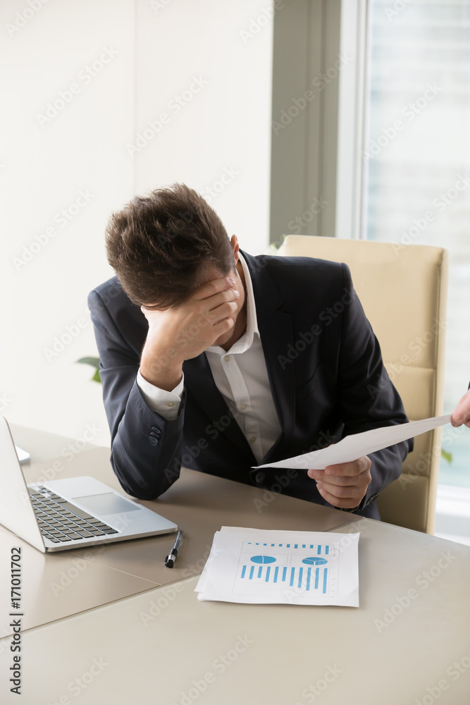 Φωτογραφία Frustrated businessman sitting at desk with laptop and business documents