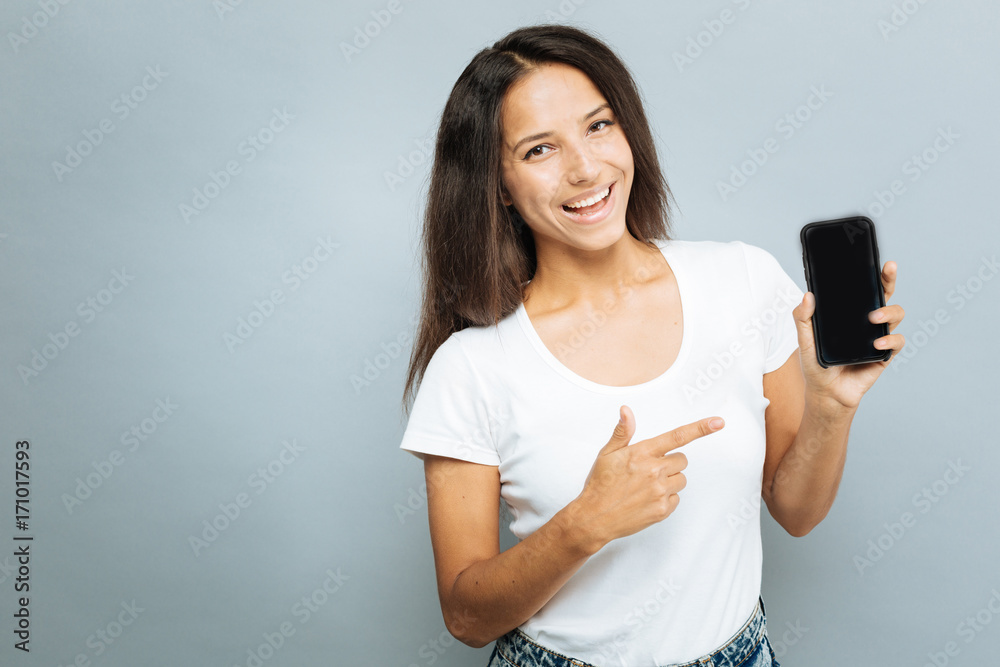Delighted young woman pointing at her mobile phone Delighted young woman pointing at her mobile phone