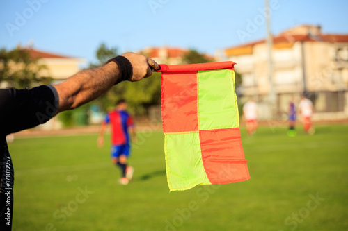 Soccer (football) referee assistant with flag on the field