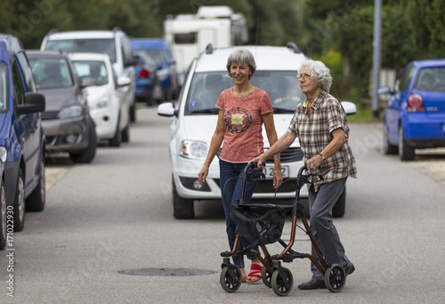 Seniorin am Rollator überquert mit ihrer Tochter die Straße